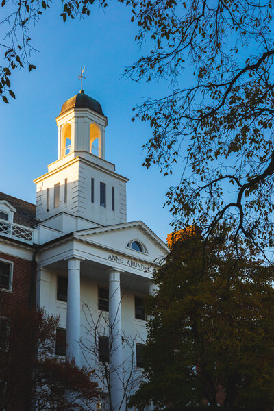 View of Anne Arundel Hall dormitory steeple at dusk with fall foliage.