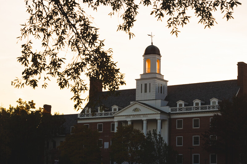 View of Anne Arundel Hall dormitory steeple at dusk with fall foliage.